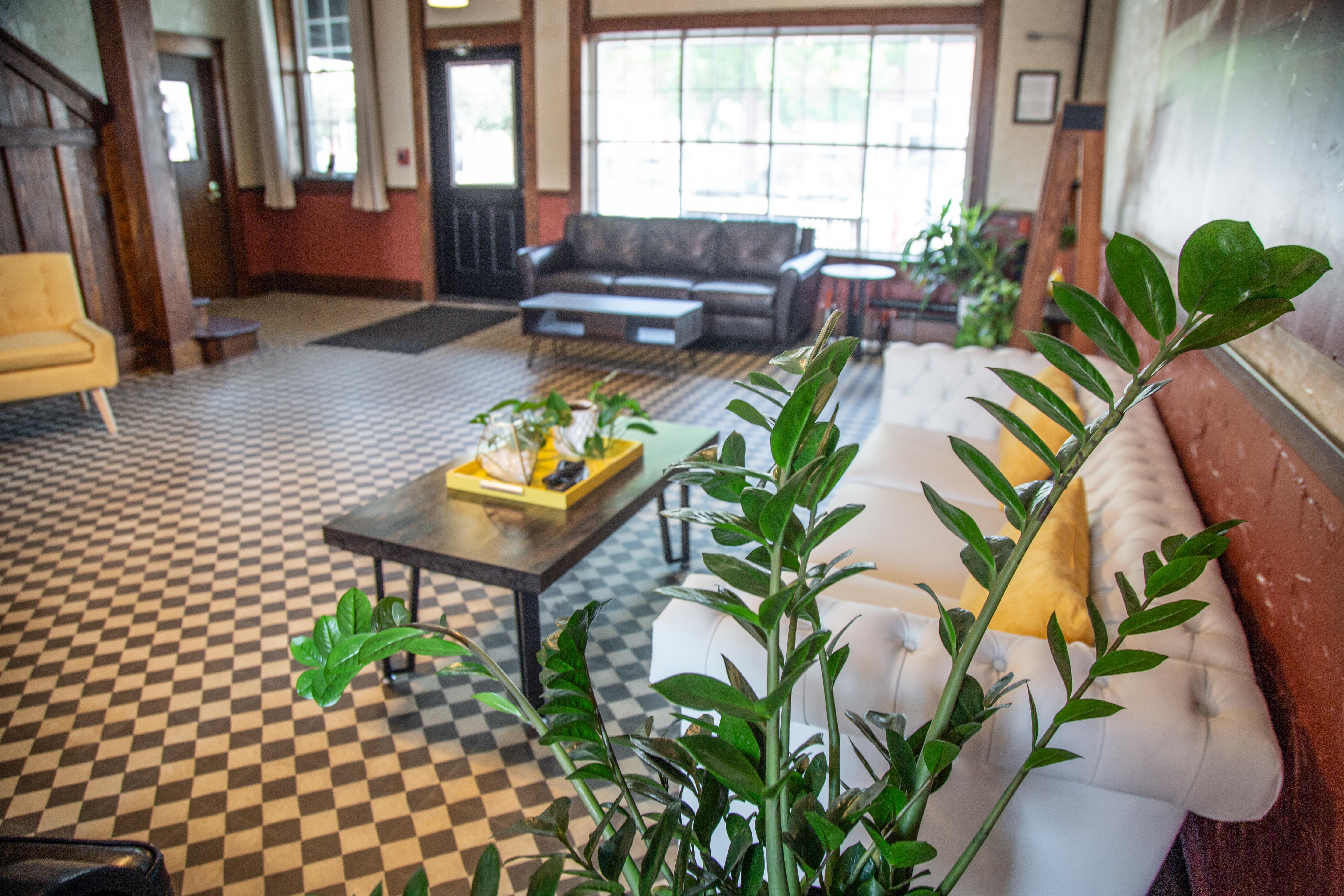 A lobby with a white sofa, a coffee table, and a plant on a checkered floor.
