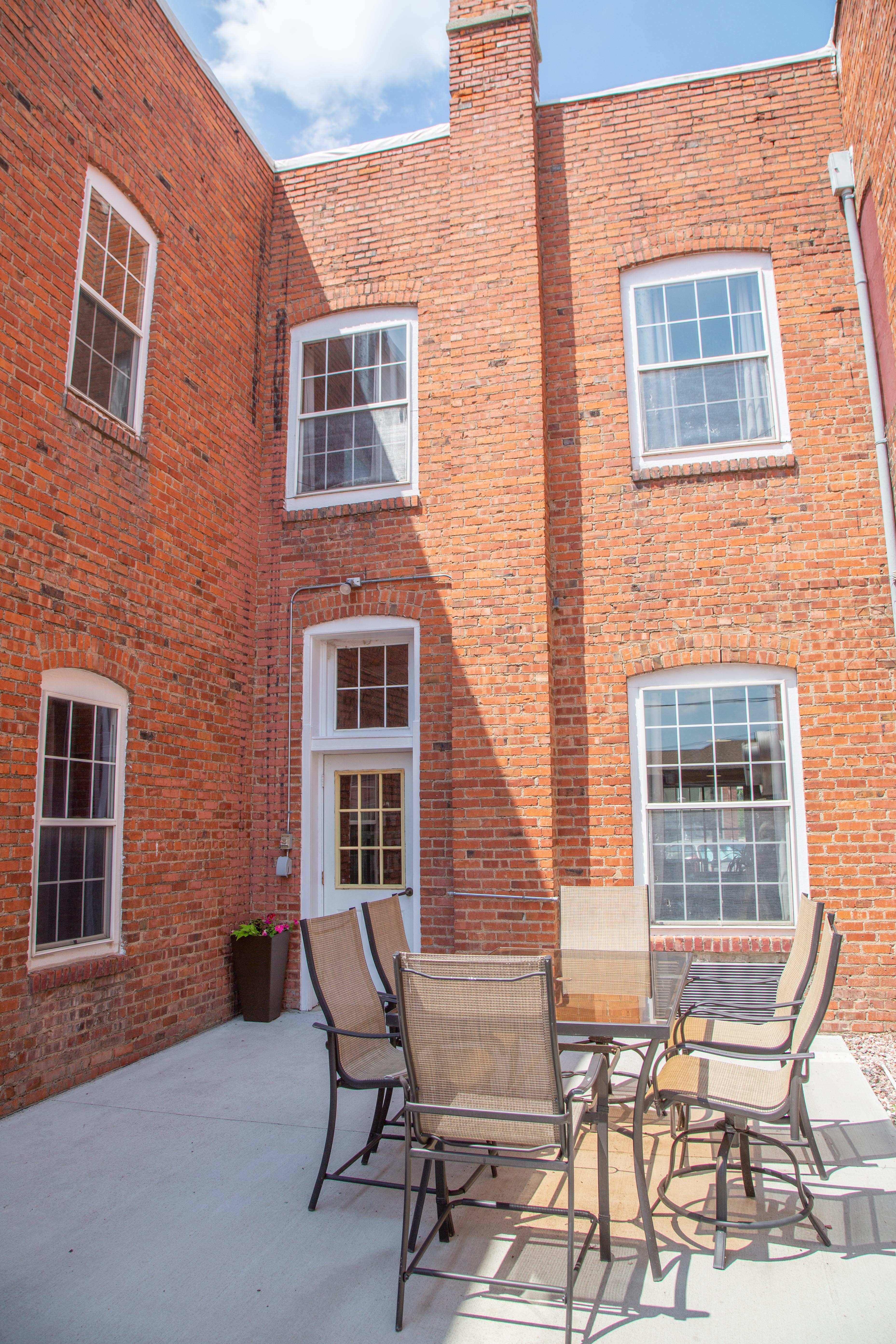 A brick building with a patio area featuring outdoor furniture.