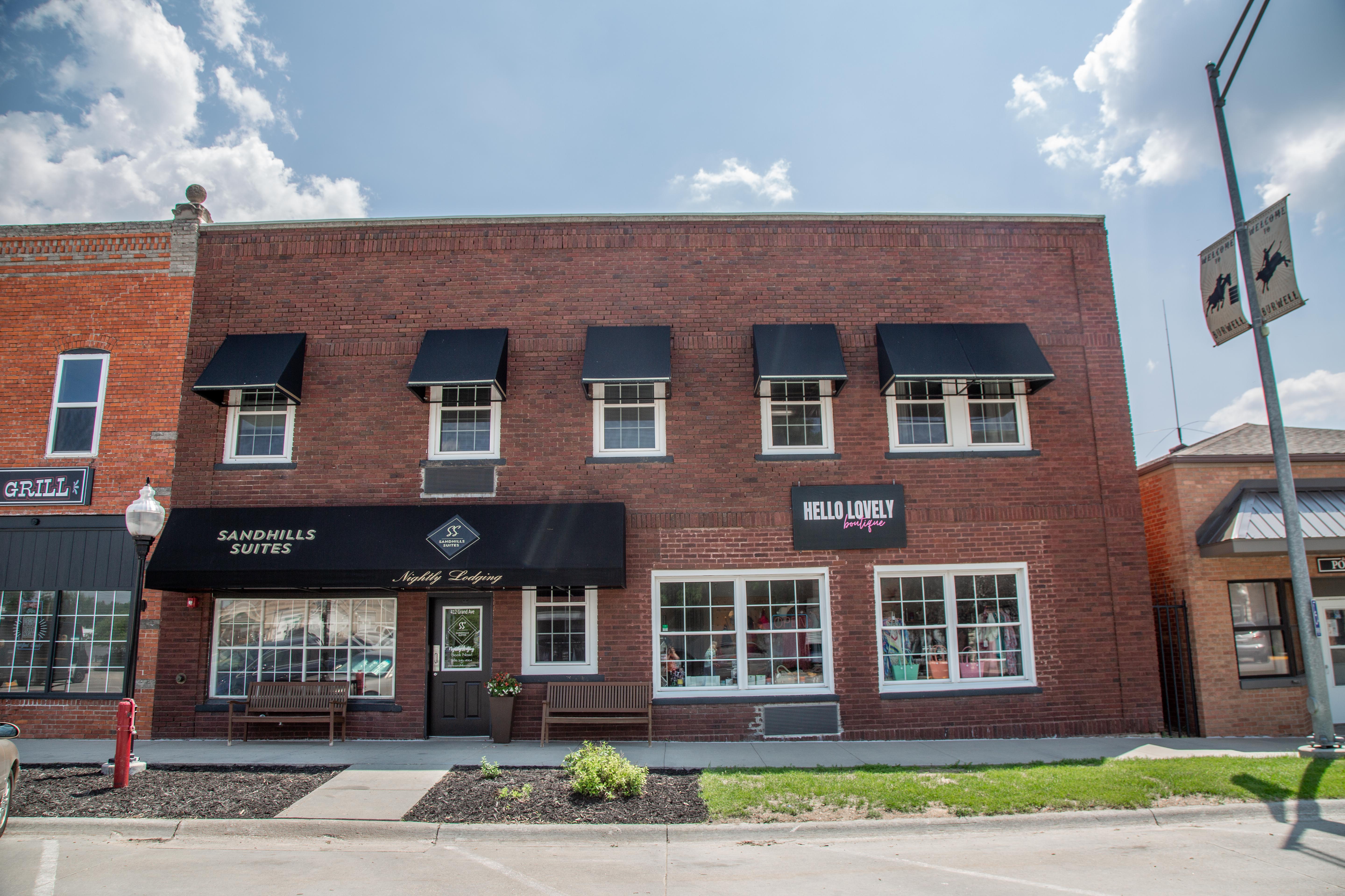 A red brick building with a black awning and signage reading 'Sandhills Suites'